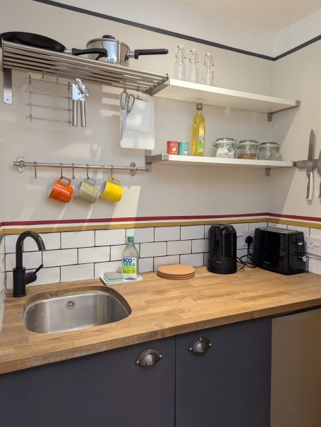 Kitchenette Modern kitchen corner with a wooden countertop, sink, shelves, and kitchen appliances.