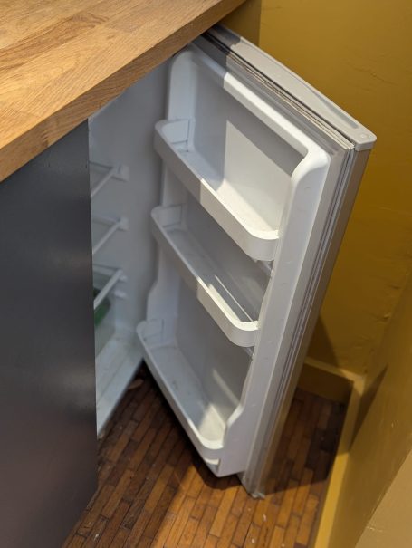 Fridge Open refrigerator displaying empty shelves against a wooden countertop.