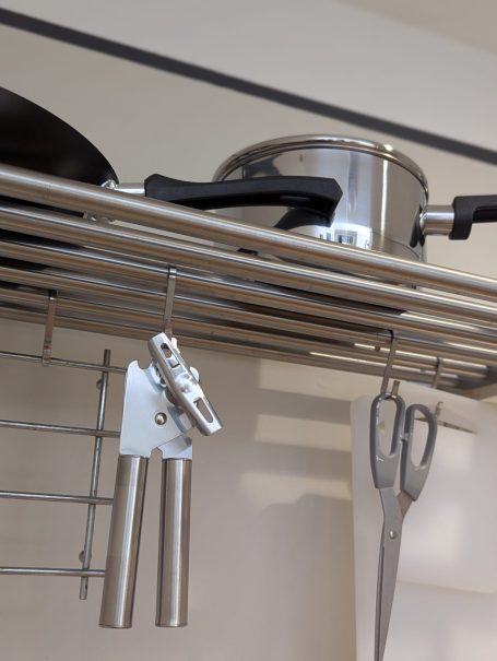 Essential utensils Metal pots and utensils hanging on a kitchen rack.