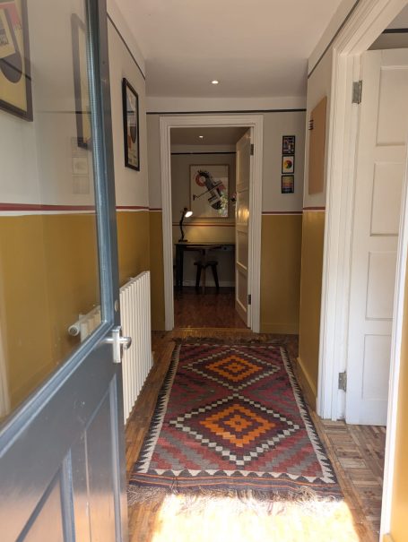 Private Area A hallway with a patterned rug, warm yellow walls, and framed pictures.