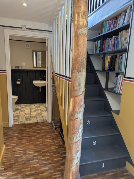 Staircase to Bedroom Interior view of a staircase leading to a book-filled shelf and a bathroom beyond.