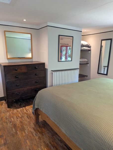 Cosy bedroom Modern bedroom with a large bed, wooden dresser, and mirrors on the walls.
