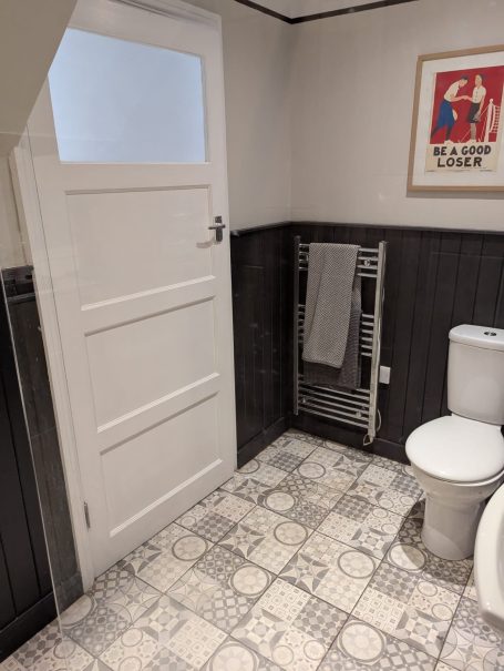 Private Bathroom White door leading to a bathroom with tiled floor, toilet, and towel rack.