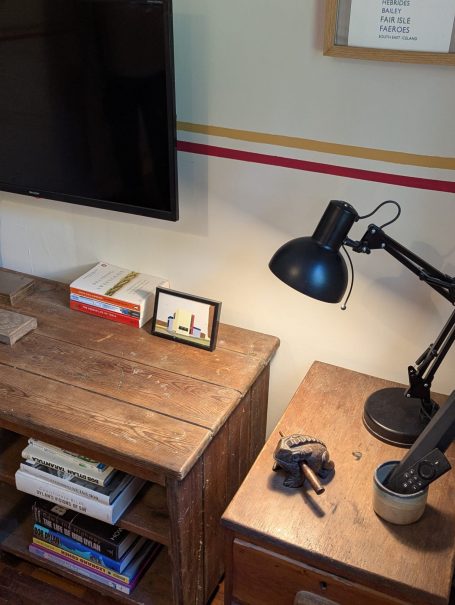 Television A wooden desk with a lamp, television, books, and a framed picture.