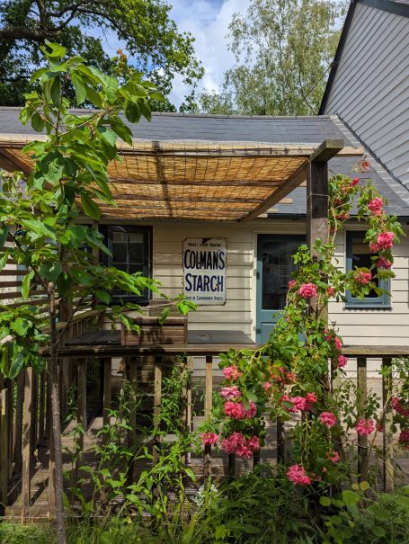A pretty and peaceful setting A quaint cottage with a wooden porch and pink flowers in front.